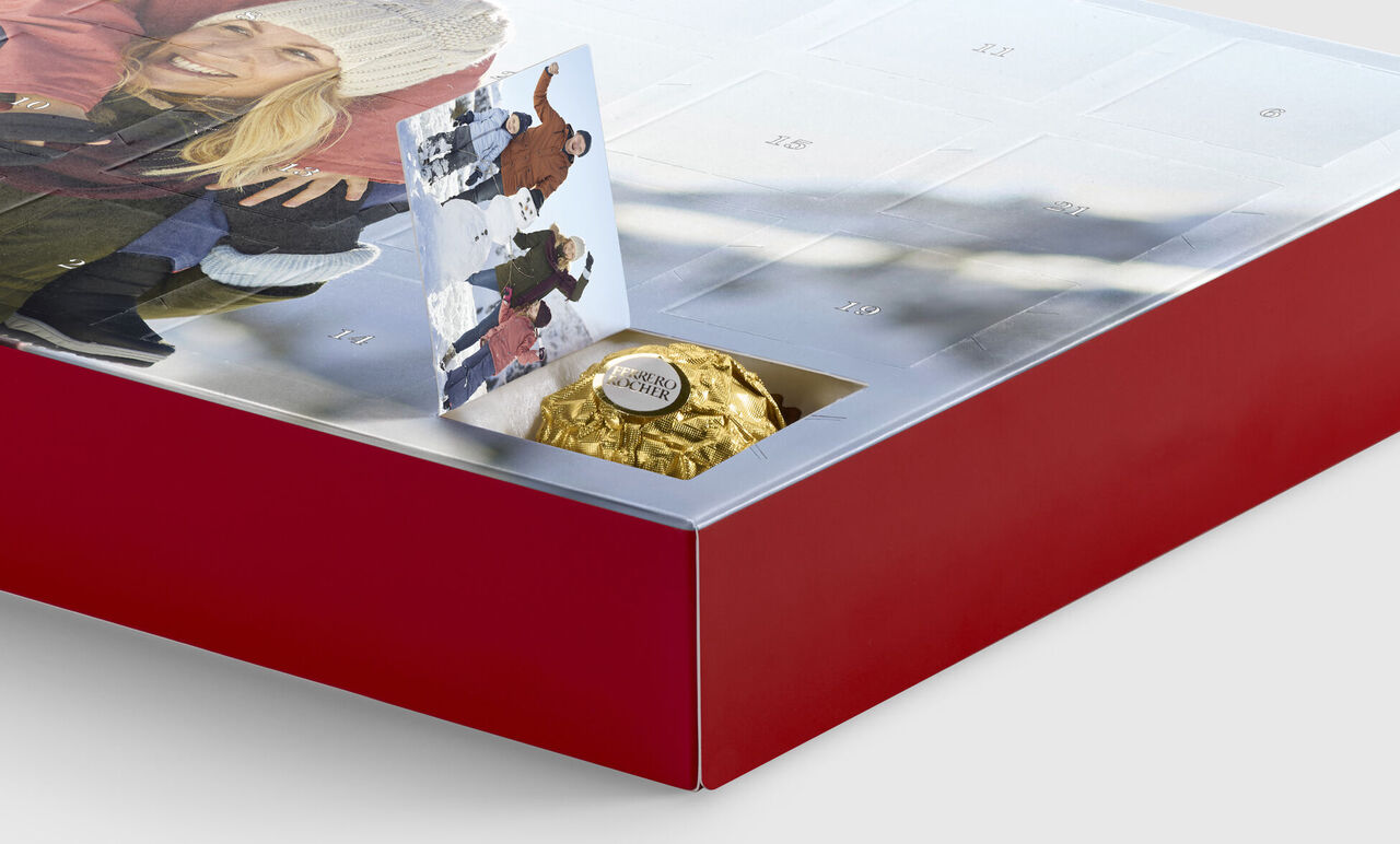 Calendario dell'avvento rosso con una pallina di cioccolato dorato e un'immagine natalizia.
