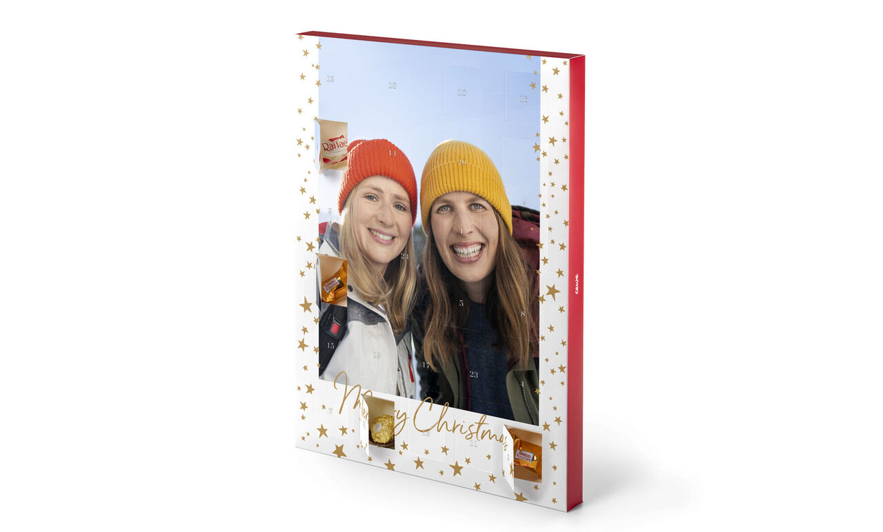 Album CEWE con design natalizio, due persone lo tengono. Sulla copertina ci sono stelle dorate e la scritta "Buon Natale".