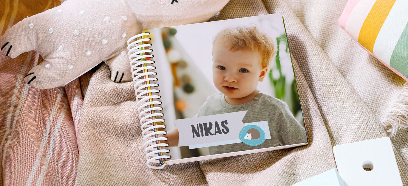 Un fotolibro CEWE con il nome 'NIKAS' su una coperta con giocattoli.
