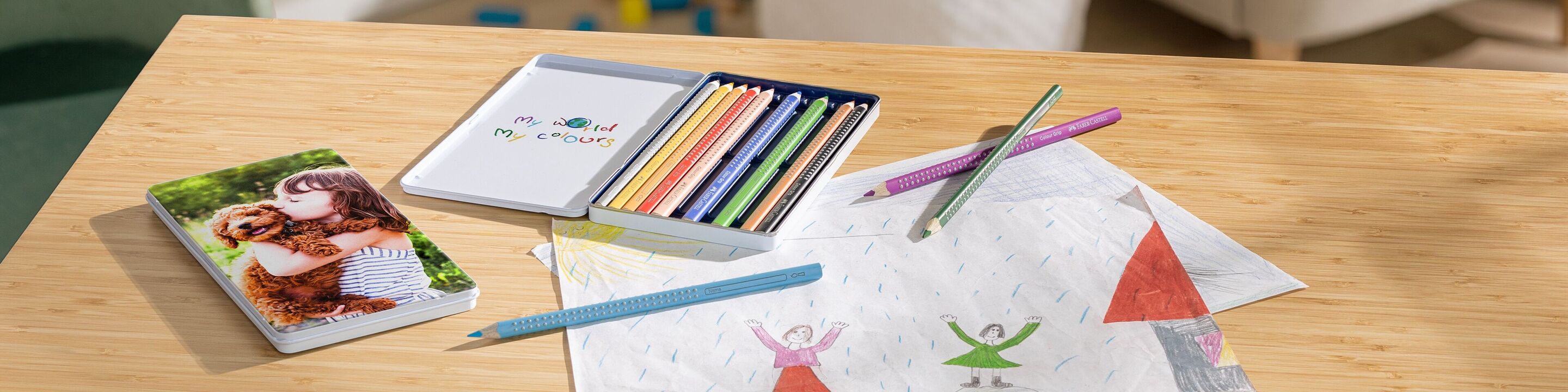 Un tavolo creativo con matite colorate, un fotolibro, un quadro e un disegno.