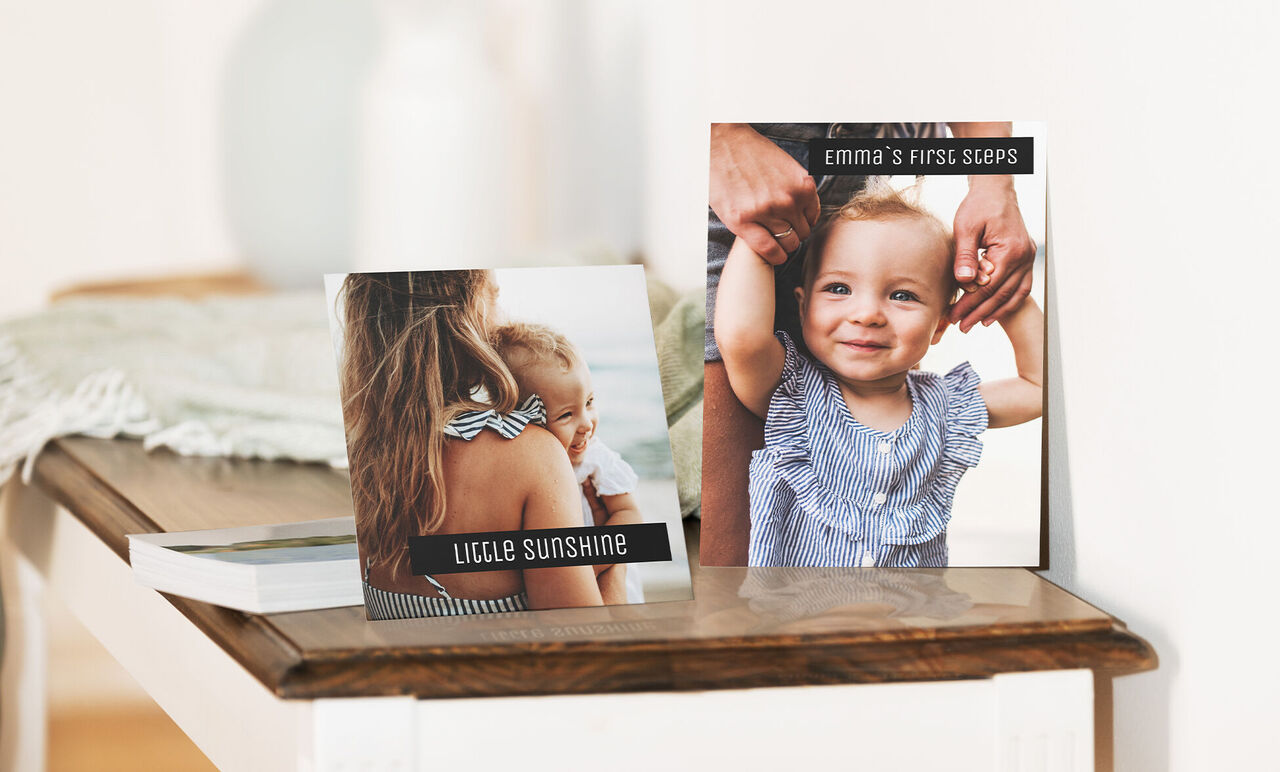 Due album fotografici creativi su un tavolo, uno con un bambino che tira un cappello.