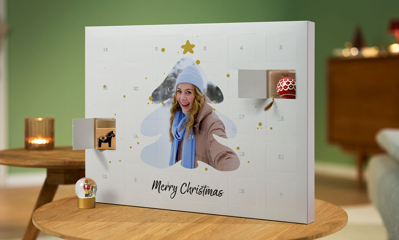 Un calendario dell'avvento aperto a forma di albero di Natale con regali e 'Buon Natale' in una stanza accogliente