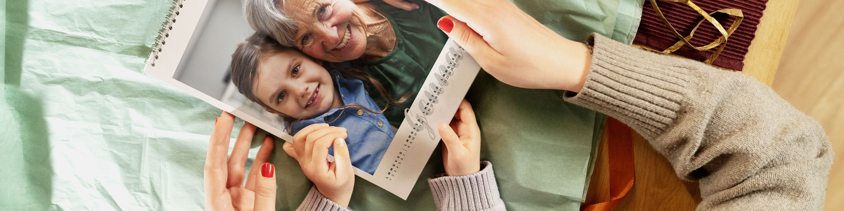 Un abbraccio tenero tra una nonna e un bambino con calendario fotografico sul tavolo.