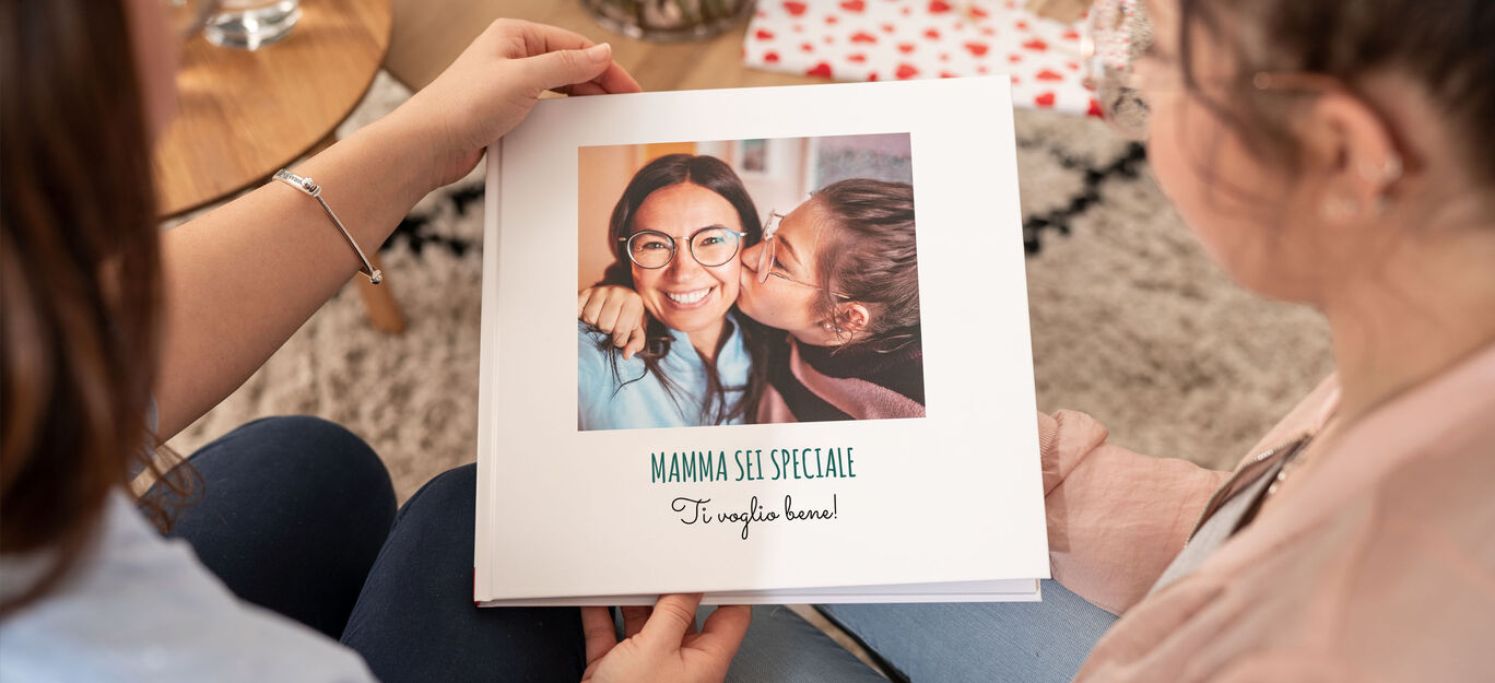 Due persone tengono un CEWE FOTOLIBRO con una copertina affettuosa.