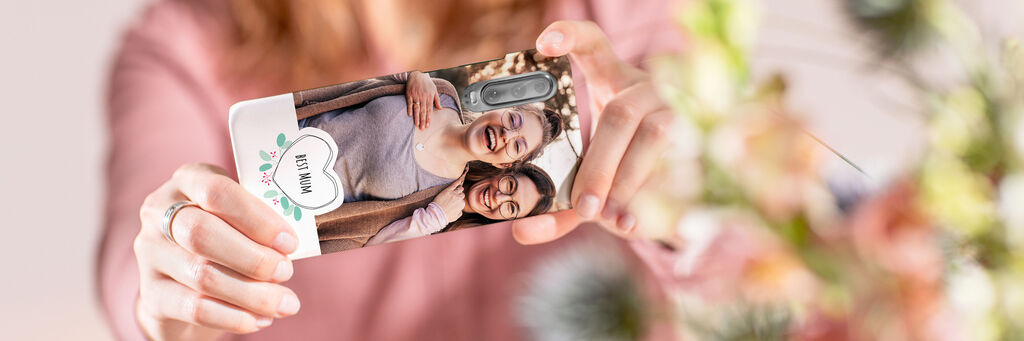 Due persone sorridono felici in camera e tengono un telefono con una custodia personalizzata.