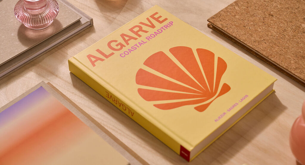 Un fotolibro CEWE è su un tavolo. La copertina è di colore giallo chiaro e riporta la parola "Algarve".