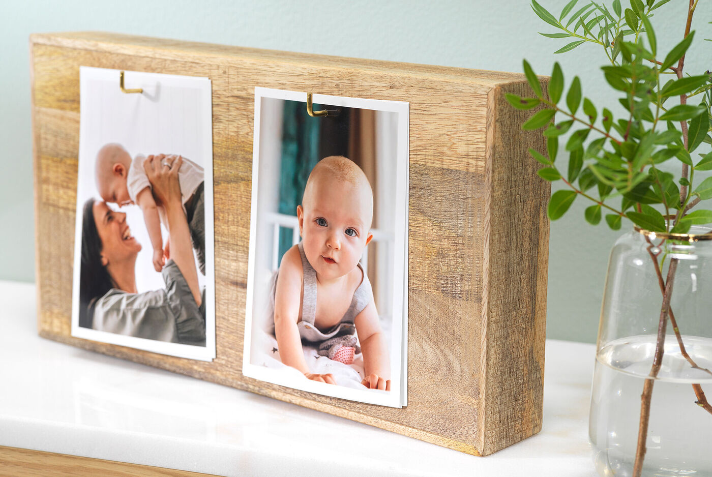 Due foto su un supporto in legno, una mostra una madre con il suo bambino, l'altra un bambino in una stanza accogliente
