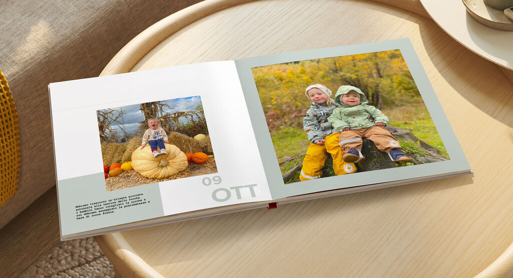 Due bambini siedono su un tronco davanti a un album fotografico, circondati da un'atmosfera autunnale e zucche, che emana gioia.
